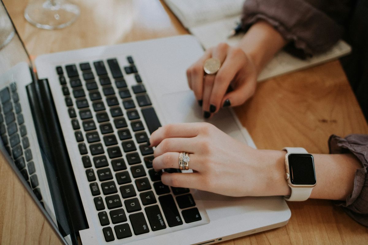 Hands typing on a laptop at a wooden table