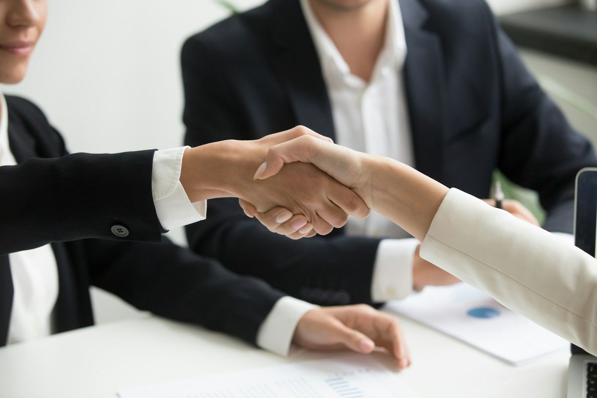 Two people shaking hands across a desk