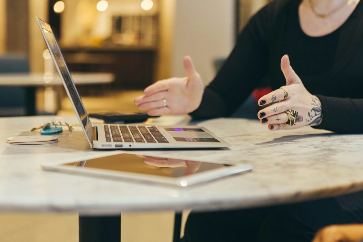 Hands mid-conversation across a table beside a laptop
