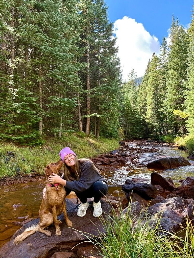Kenzie hugging Bailey beside a mountain creek