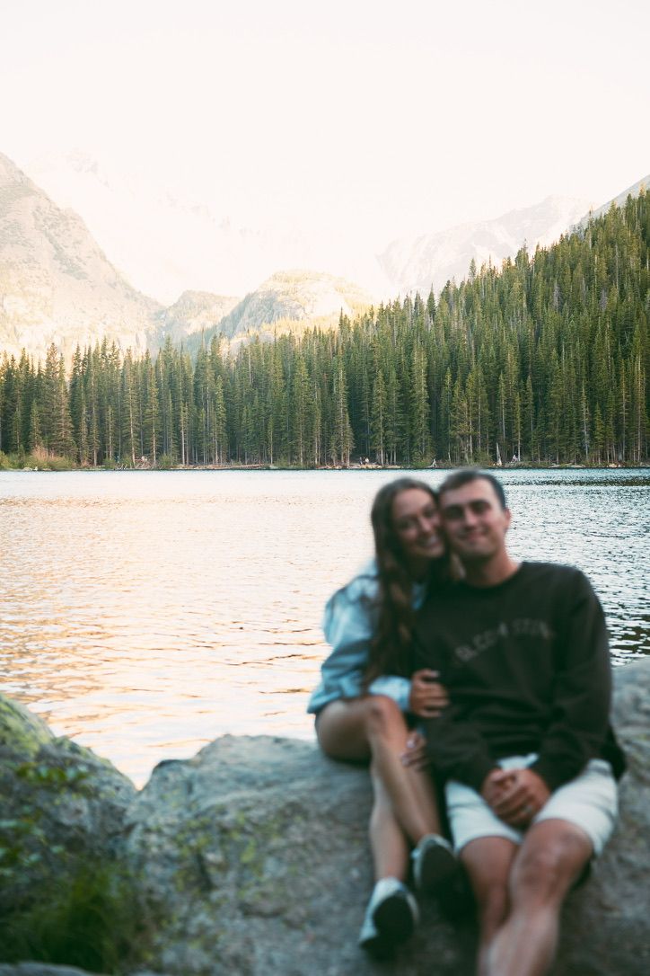 Kenzie and Justin sitting by a mountain lake at sunset, softly out of focus